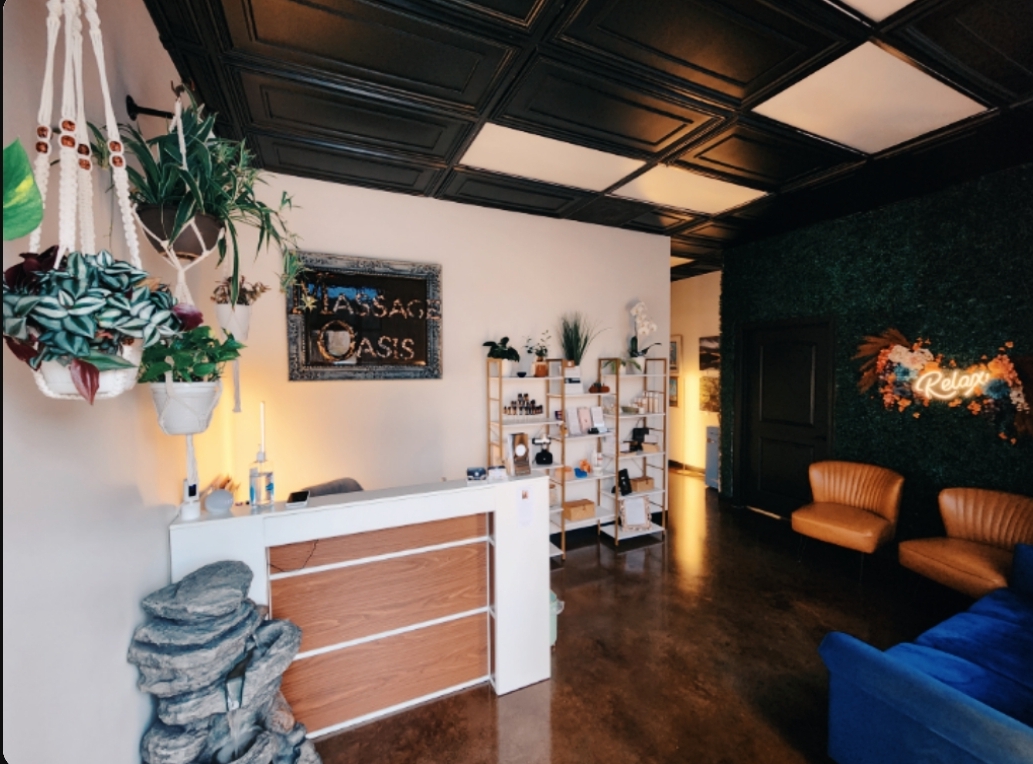 Our lobby with the Massage Oasis sign, a white reception desk and leather armchairs